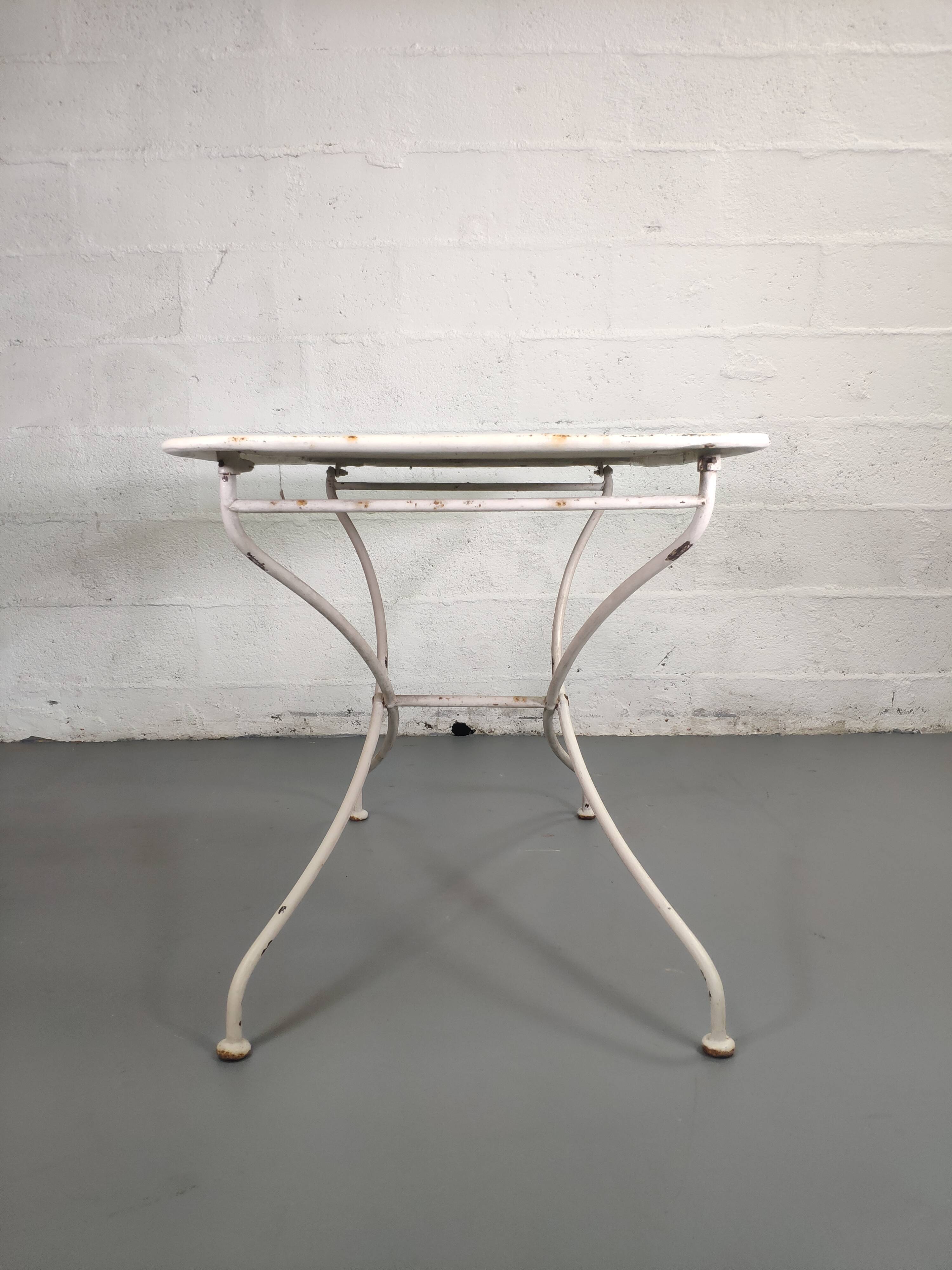 Old folding garden table in white wrought iron