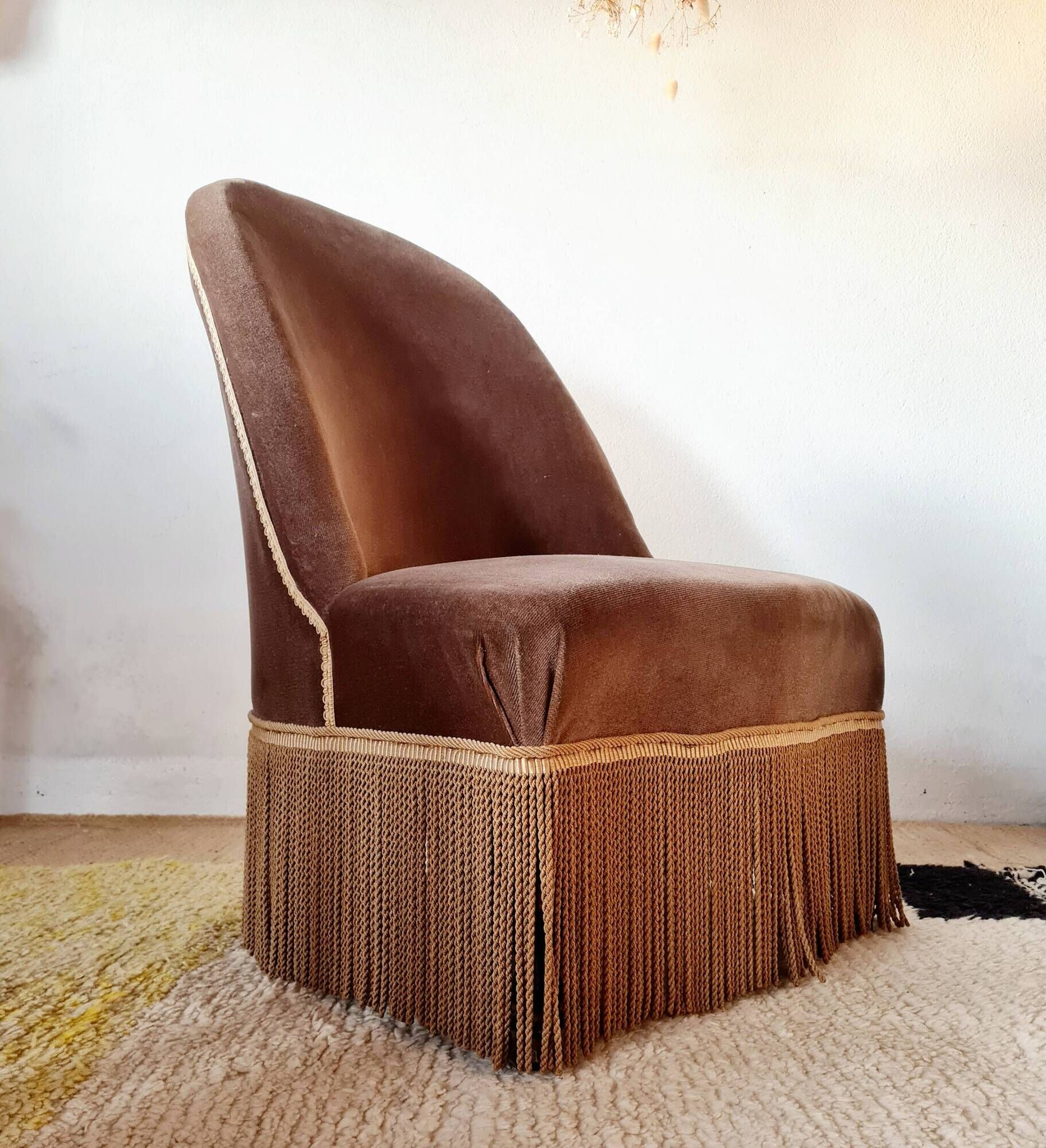 Brown velvet crapaud armchair with fringes and sculpted legs.