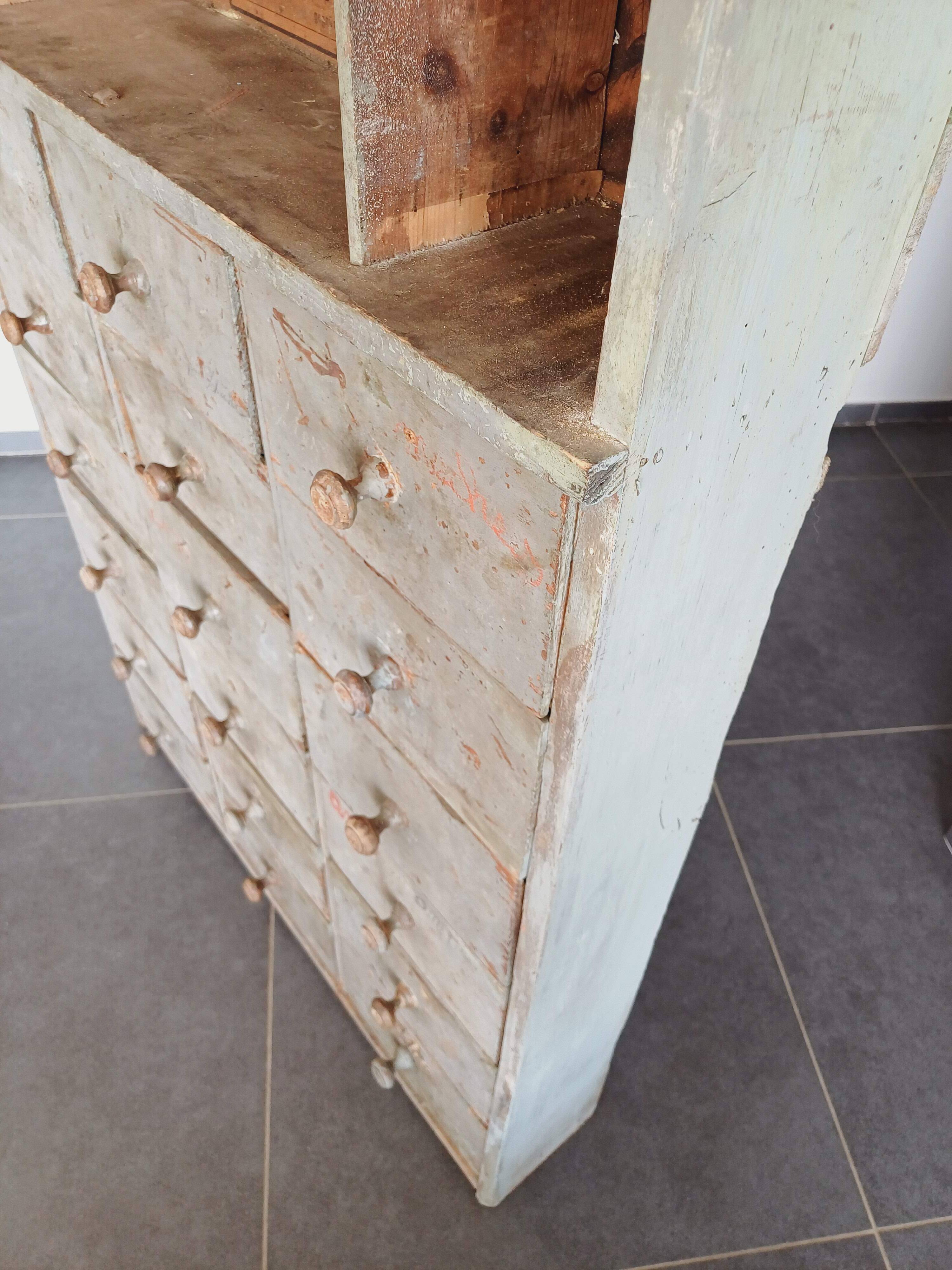 Craft cabinet with drawers with a very old tobacco advertisement in the background