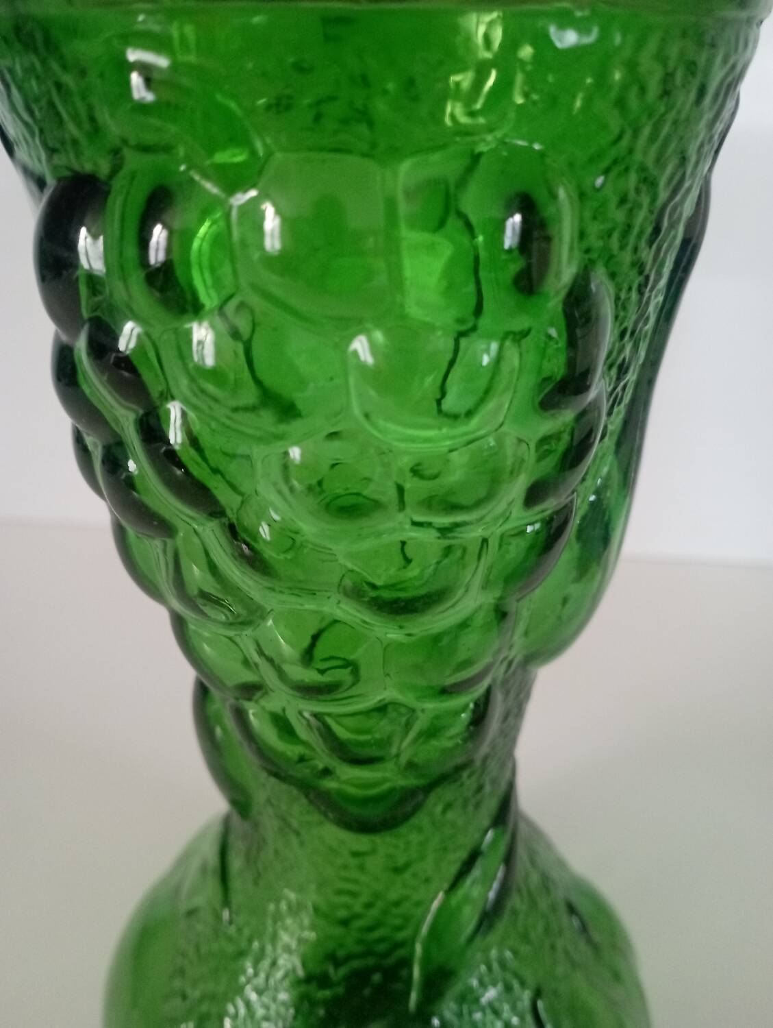 Green glass vase decorated with bunch of grapes and fruits