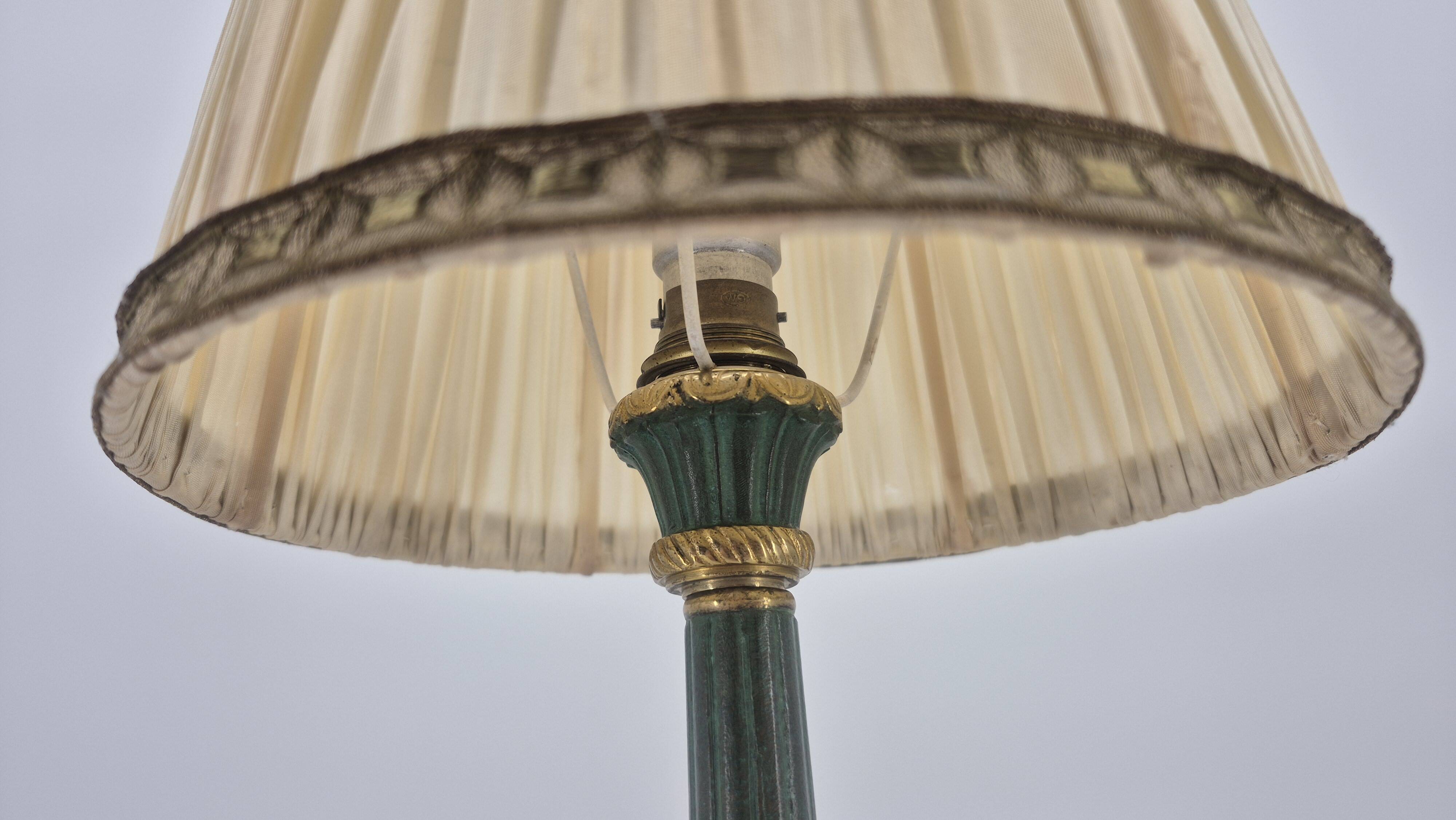 Brass table lamp with green patina and empire-style fabric shade.