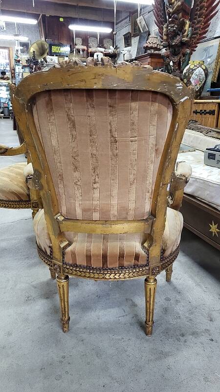 A pair of gilded wooden armchairs in the Louis XVI style.