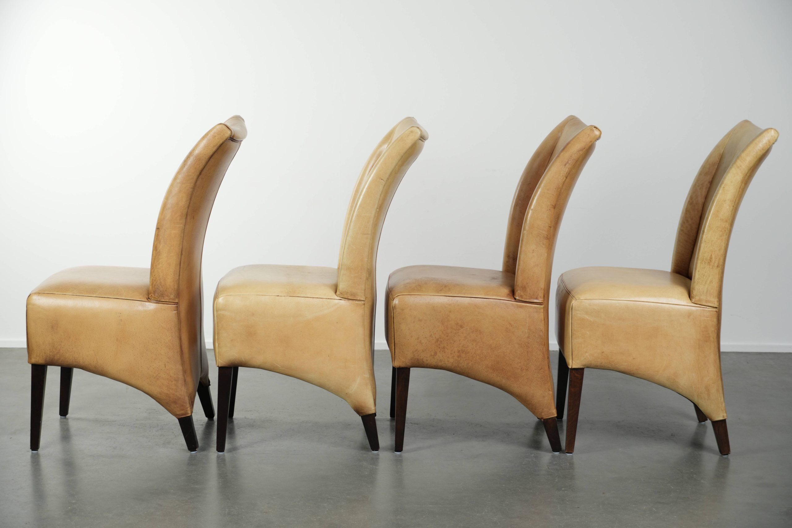 Ensemble de quatre chaises de salle à manger en cuir de vache avec un siège confortable et un dossier haut.