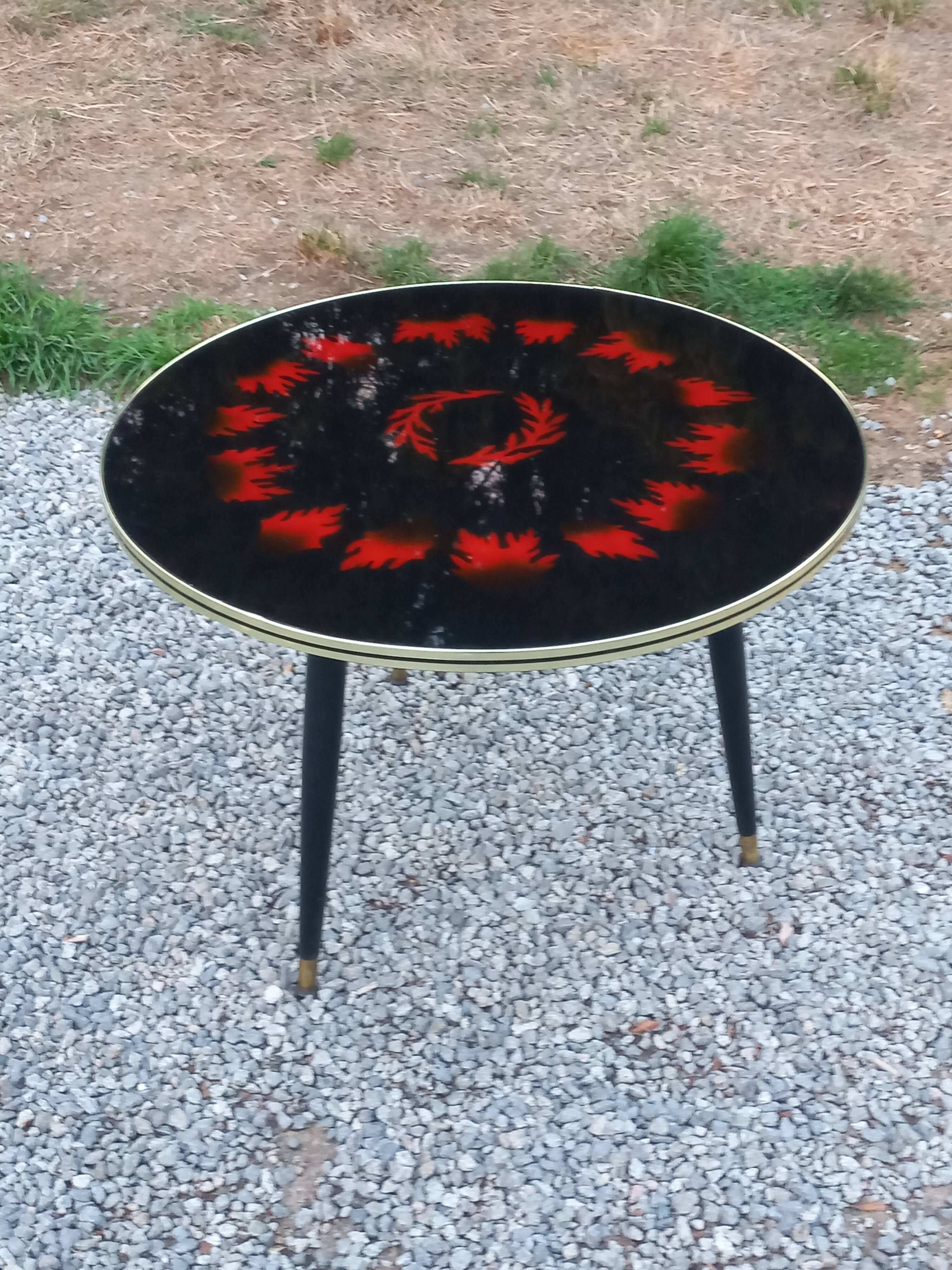 Vintage coffee table with glass top and tripod legs in blackened wood from the 1960s.
