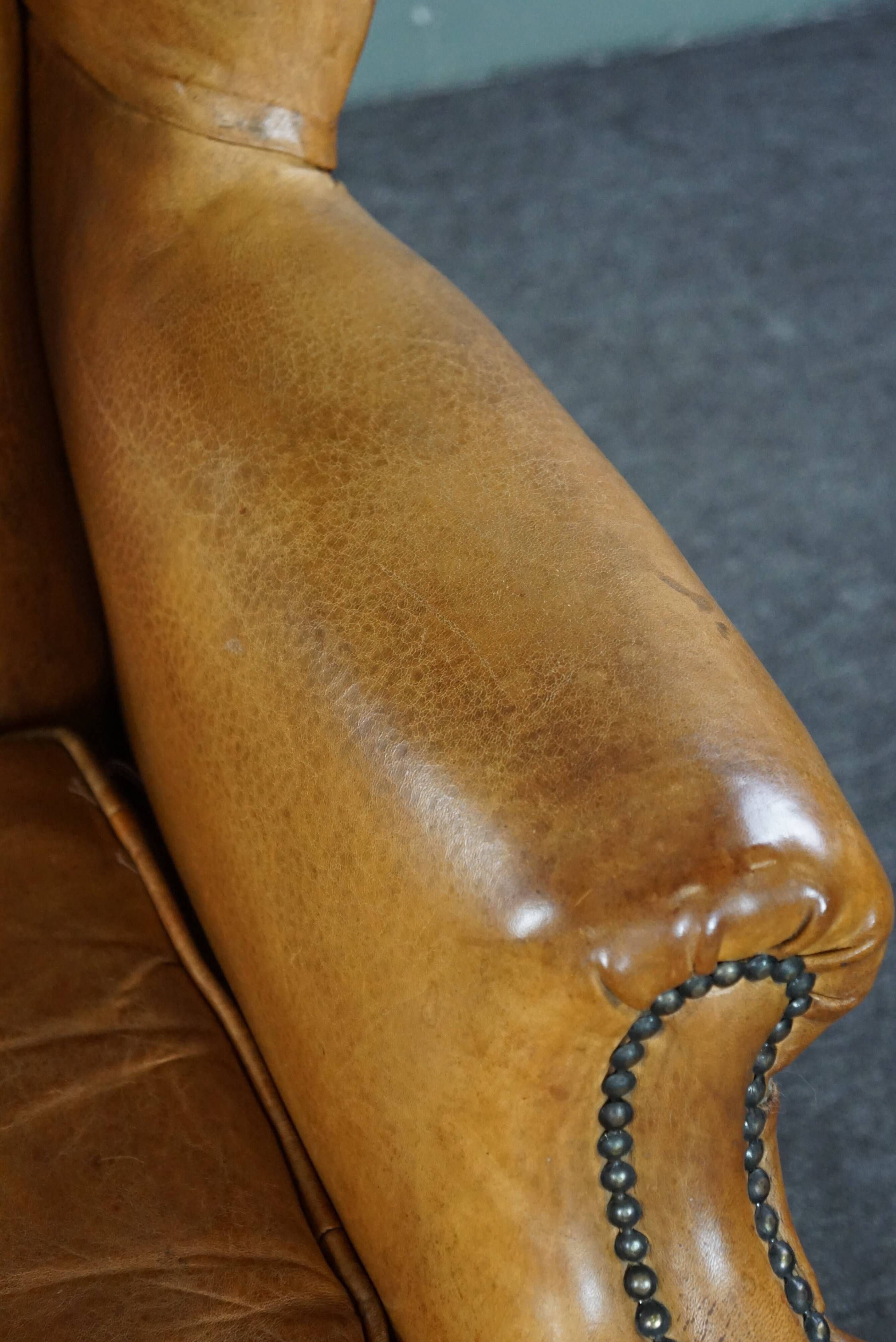 Old wingback armchair made of sheep leather in a correct condition