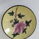 A pair of vintage Chinese decorative plates with floral designs on a yellow background.