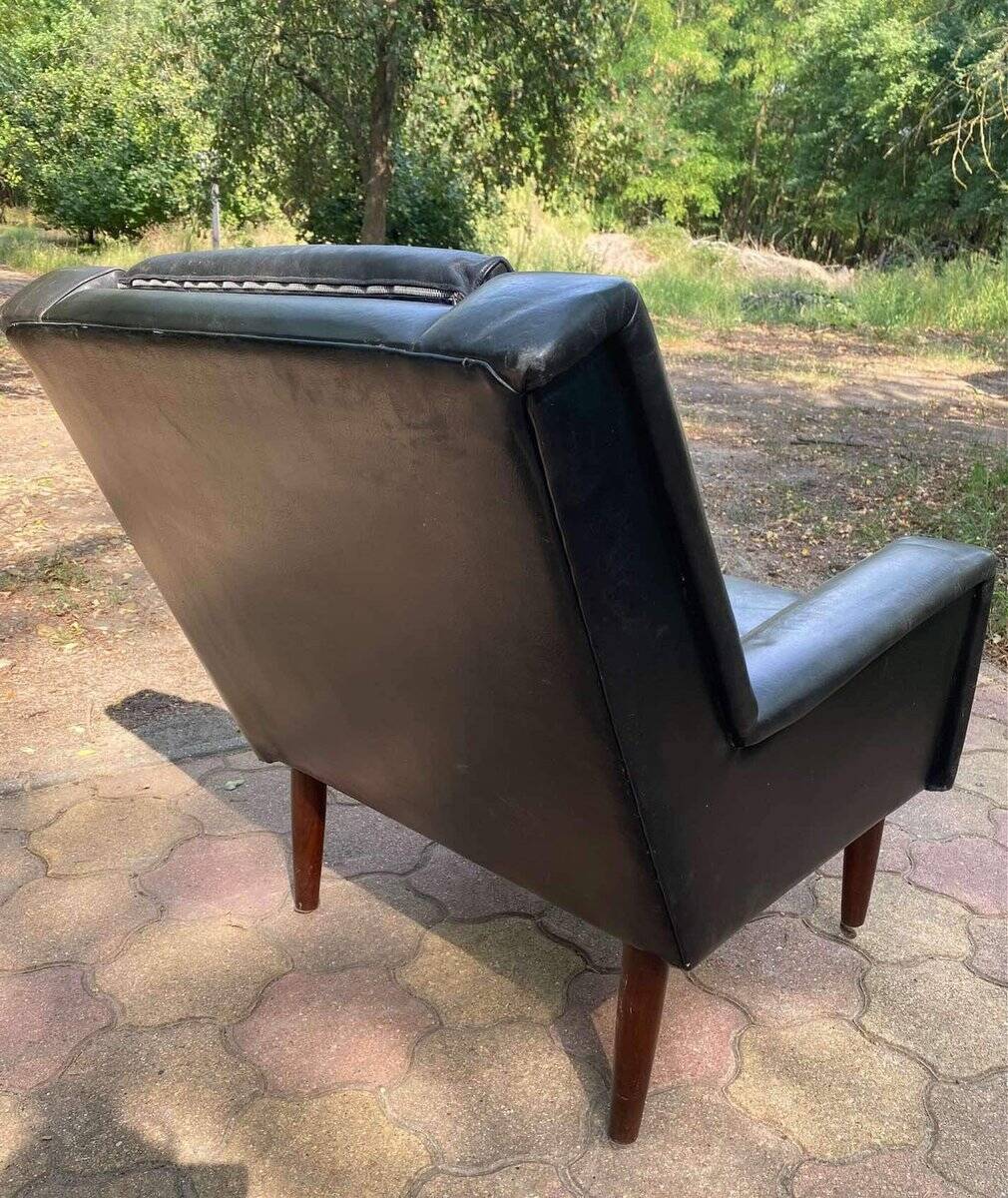Mid-Century Italian armchair from the 1960s in black leather and dark wood, with a tufted backrest.