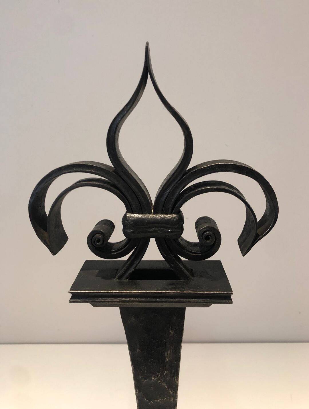 Important pair of wrought iron andirons with torch in heraldic fleur-de-lis design.