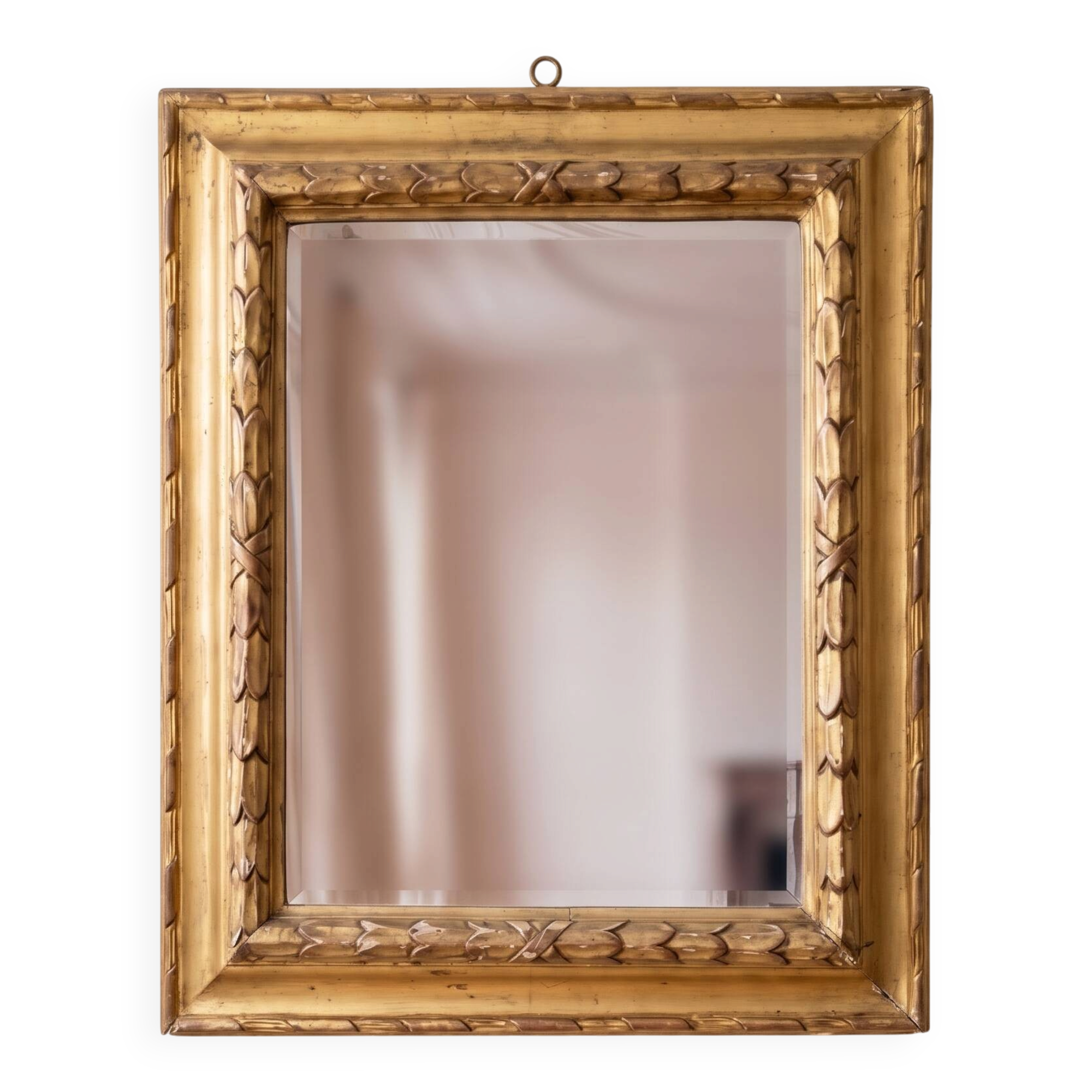 Antique wall mirror with a carved gilded frame featuring leaf motifs.