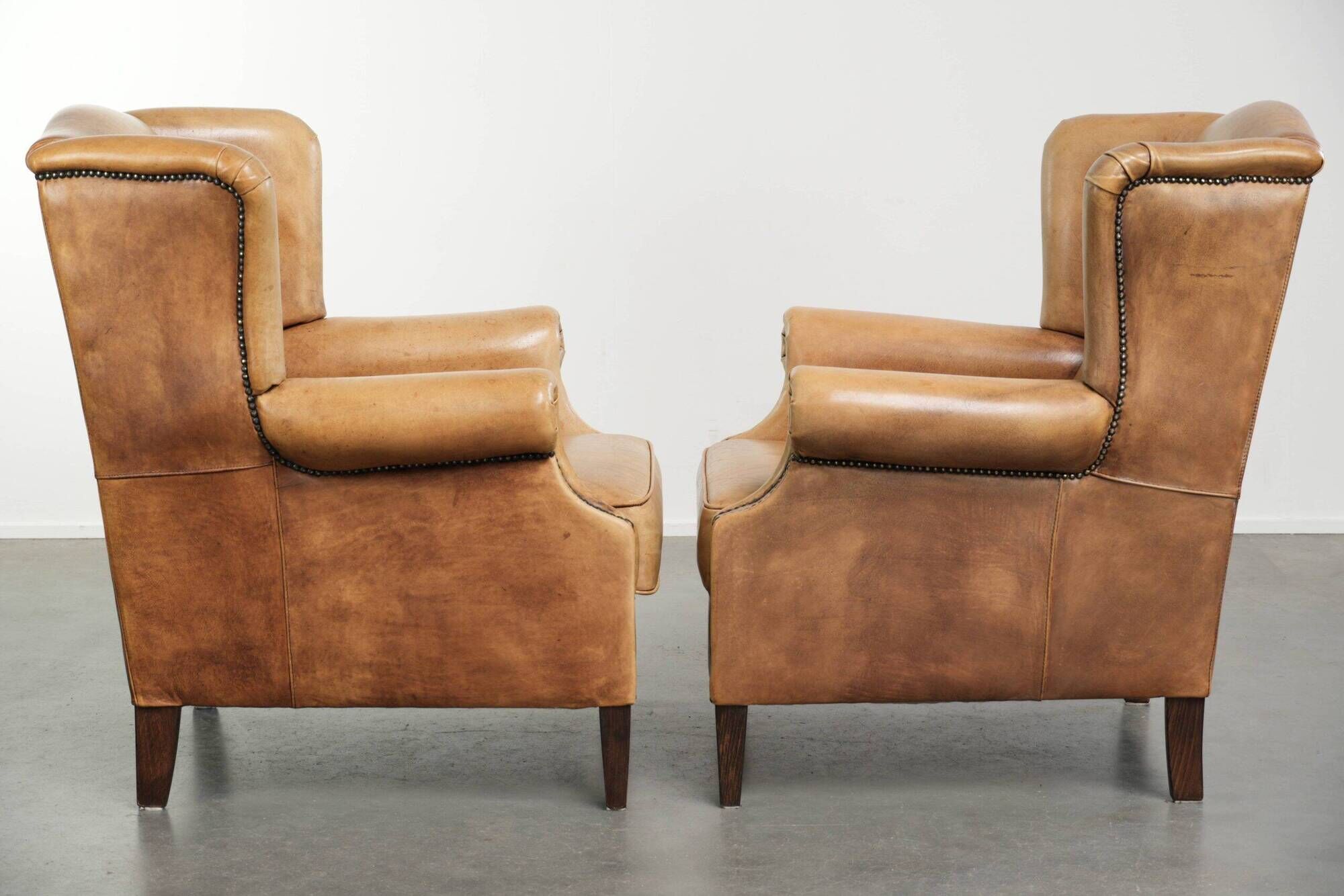 Set of two light cowhide wingback armchairs with a timeless English look