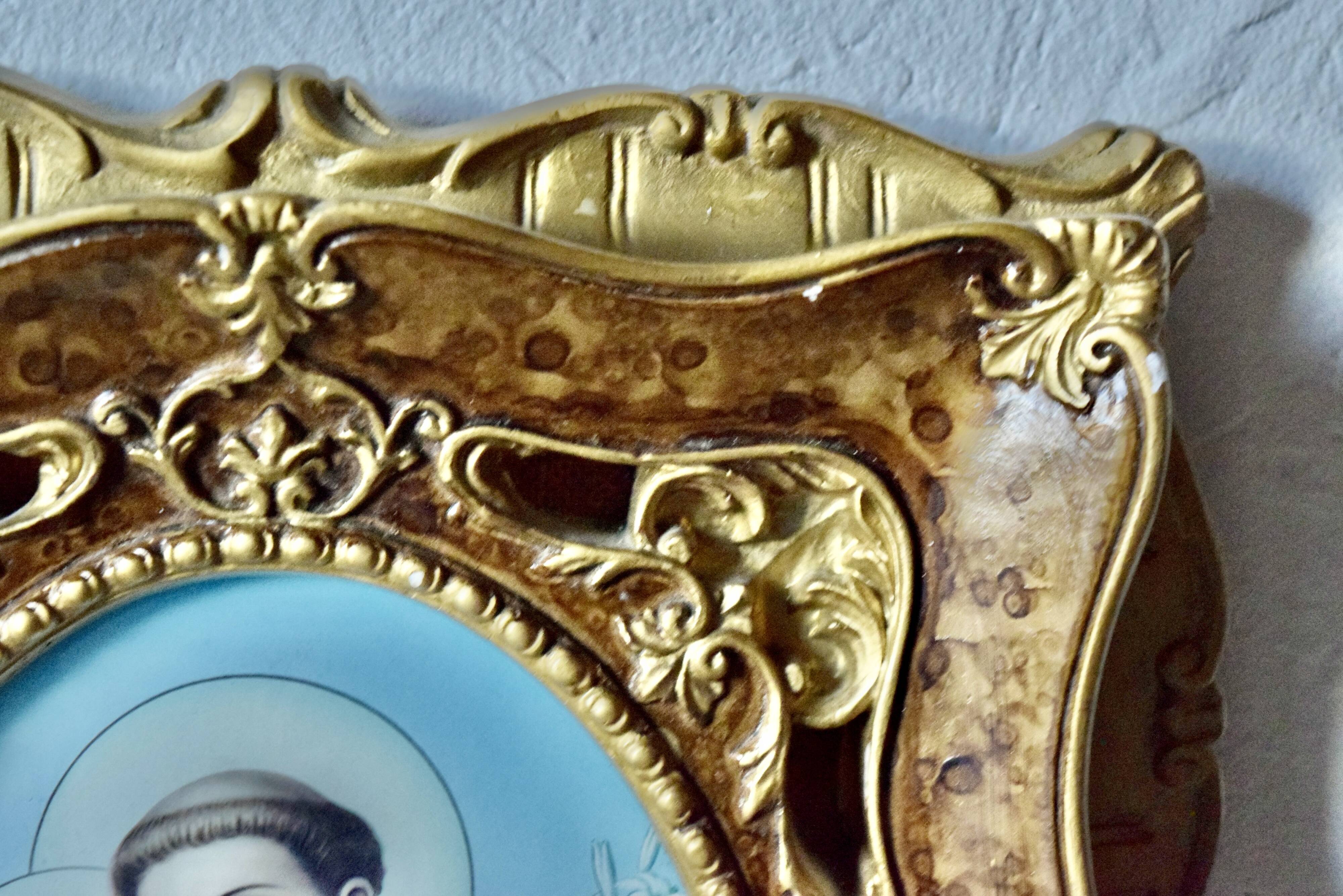 Old religious light frame in gilded stucco and curved glass