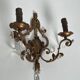 Pair of patinated wrought iron wall sconces with golden acanthus leaves and crystals.