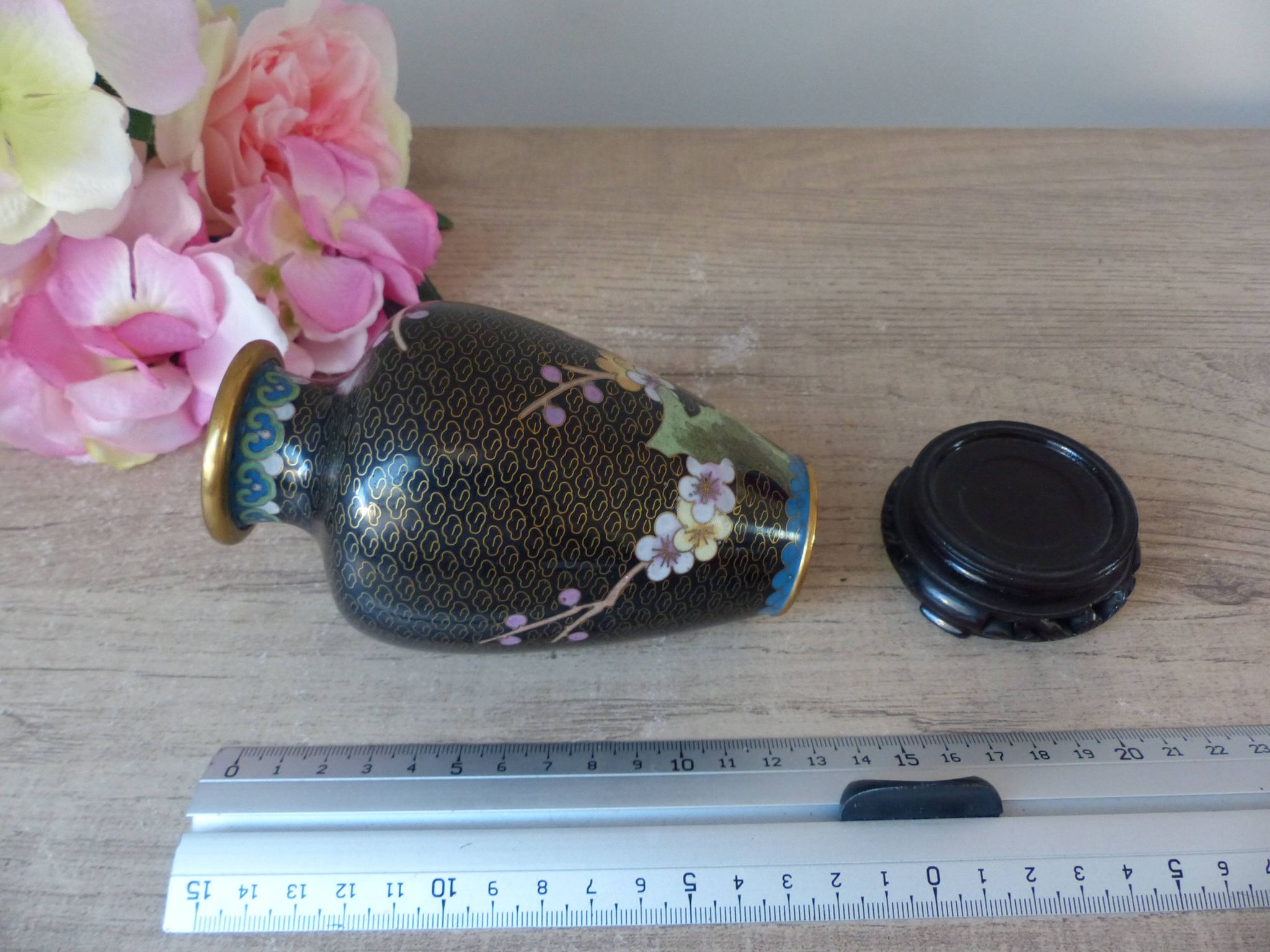 Small black cloisonné vase decorated with yellow and pink cherry blossoms, vase on wooden base