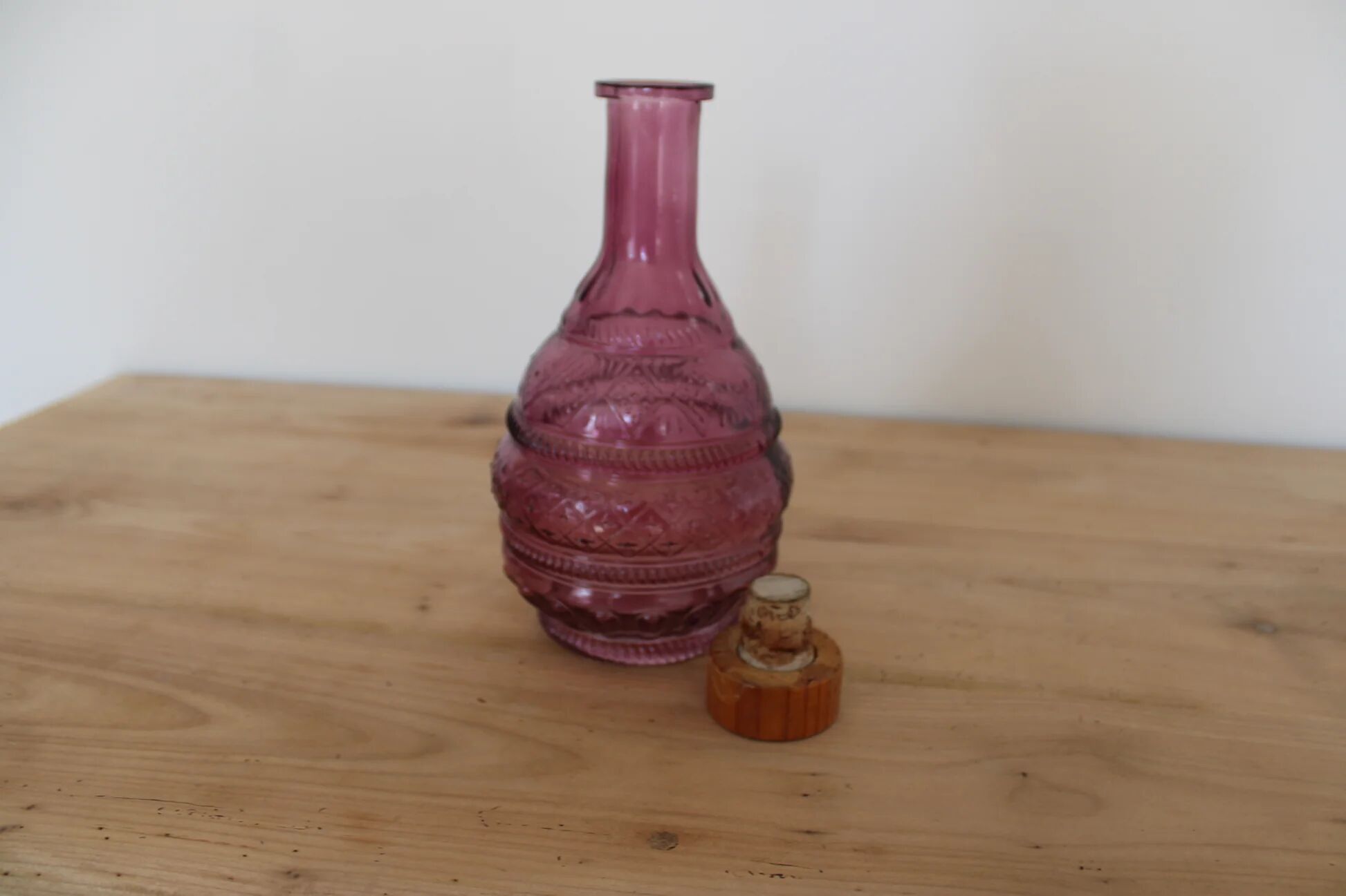 Vintage pink pressed glass carafe – retro decorative bottle with wooden stopper.