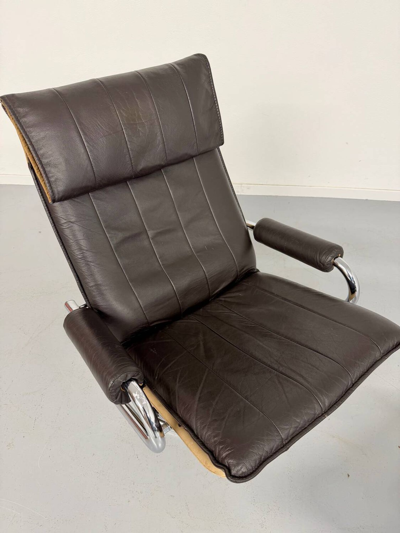 Vintage leather reclining armchair and its 1970s designer ottoman.