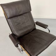 Vintage leather reclining armchair and its 1970s designer ottoman.