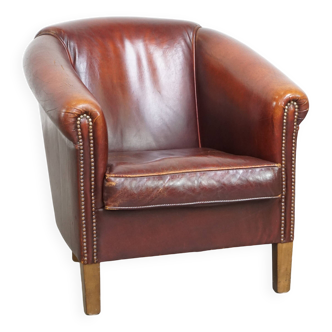 Comfortable, rugged cognac-colored sheepskin club armchair with a characteristic seat cushion