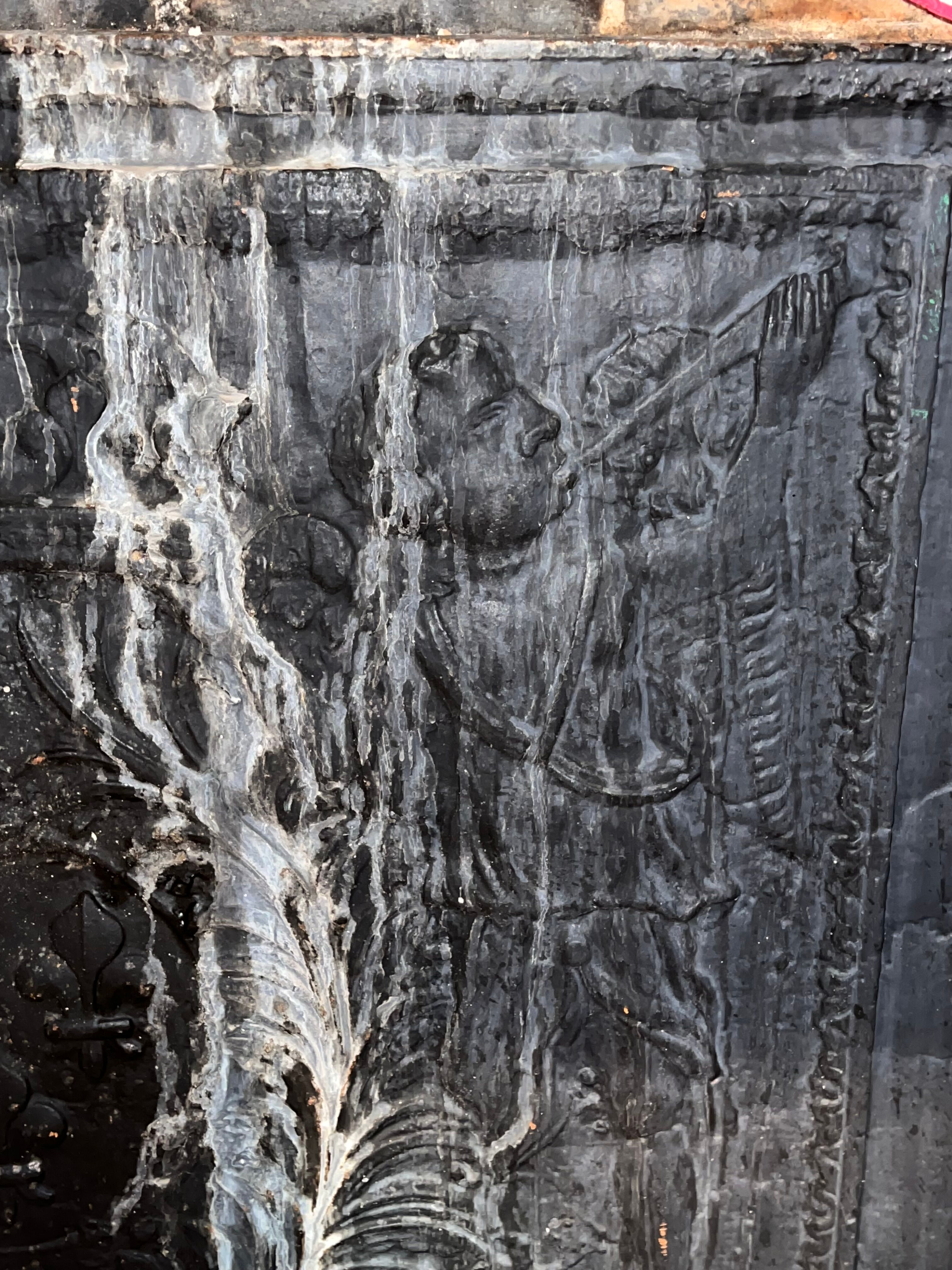 huge old fireplace plate has decoration of angels, crown and fleurs-de-lis