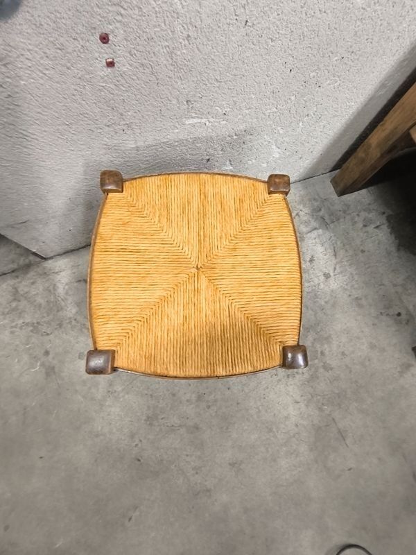 Rustic wooden stool with a straw seat.