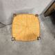 Rustic wooden stool with a straw seat.