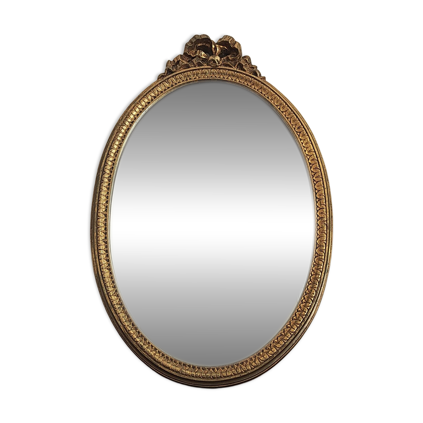 Vintage oval mirror with a carved wooden frame in gold, decorated with a bow.