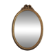 Vintage oval mirror with a carved wooden frame in gold, decorated with a bow.