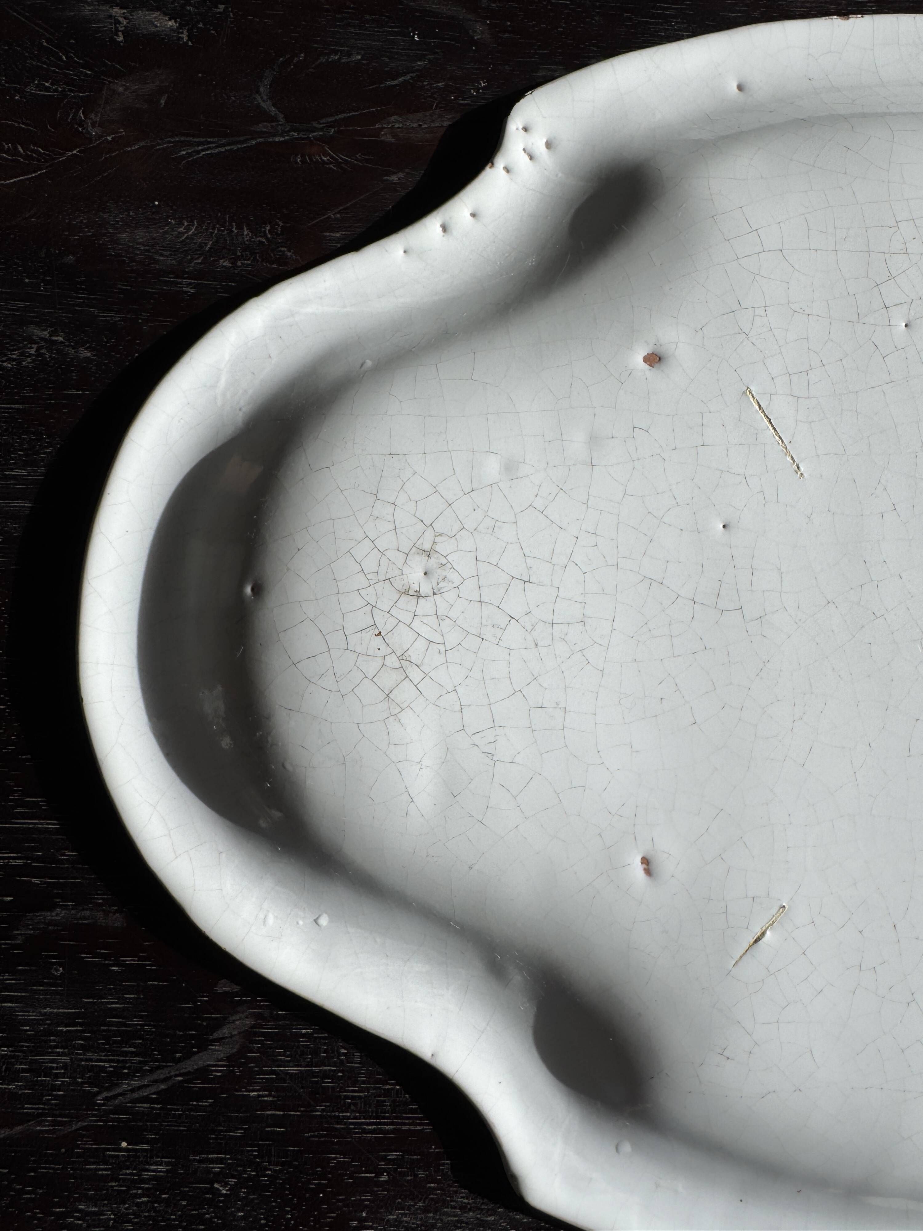 Antique oval-shaped white crackled faience plate with a scalloped edge.