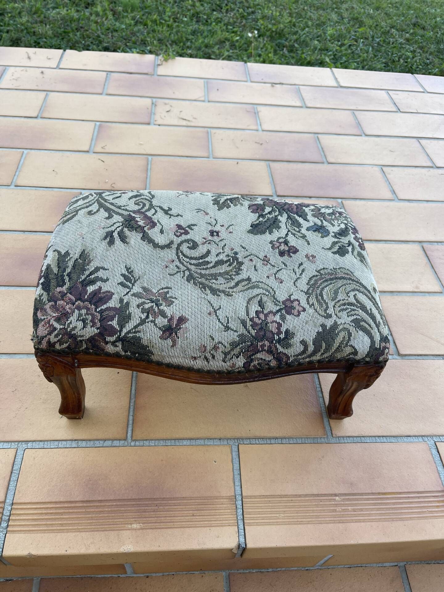 Antique wooden footstool with hand-carved details and floral upholstery –