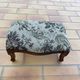 Antique wooden footstool with hand-carved details and floral upholstery –