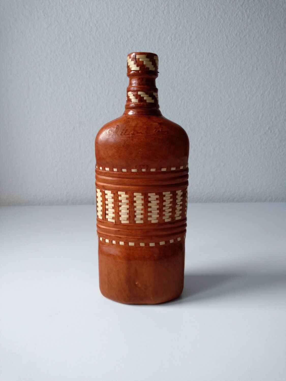 Vintage glass bottle covered with light brown leather and wicker