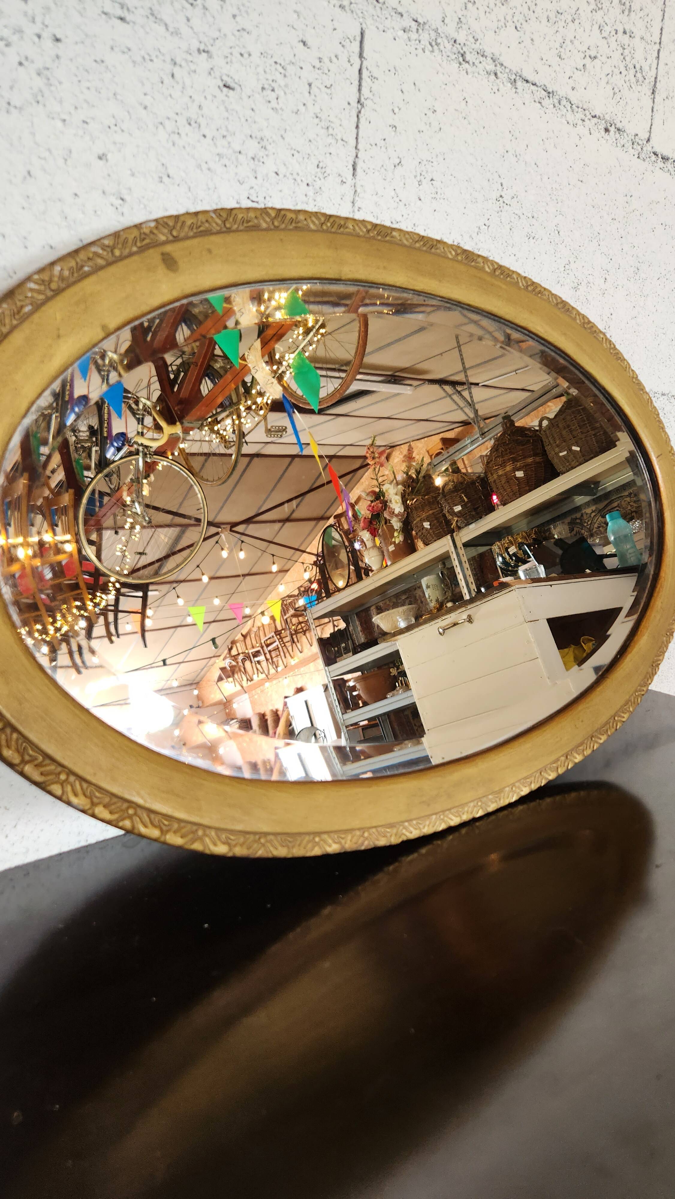 Antique oval mirror with a gilded frame, bevelled glass.