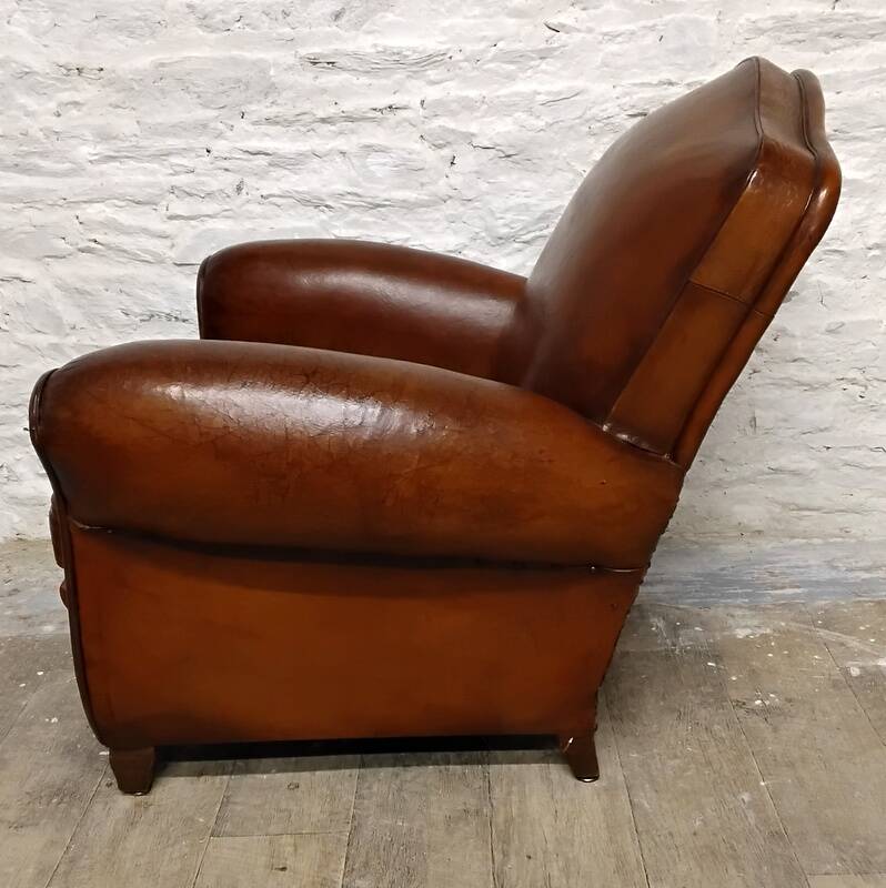 Antique club chair with gendarme hat back