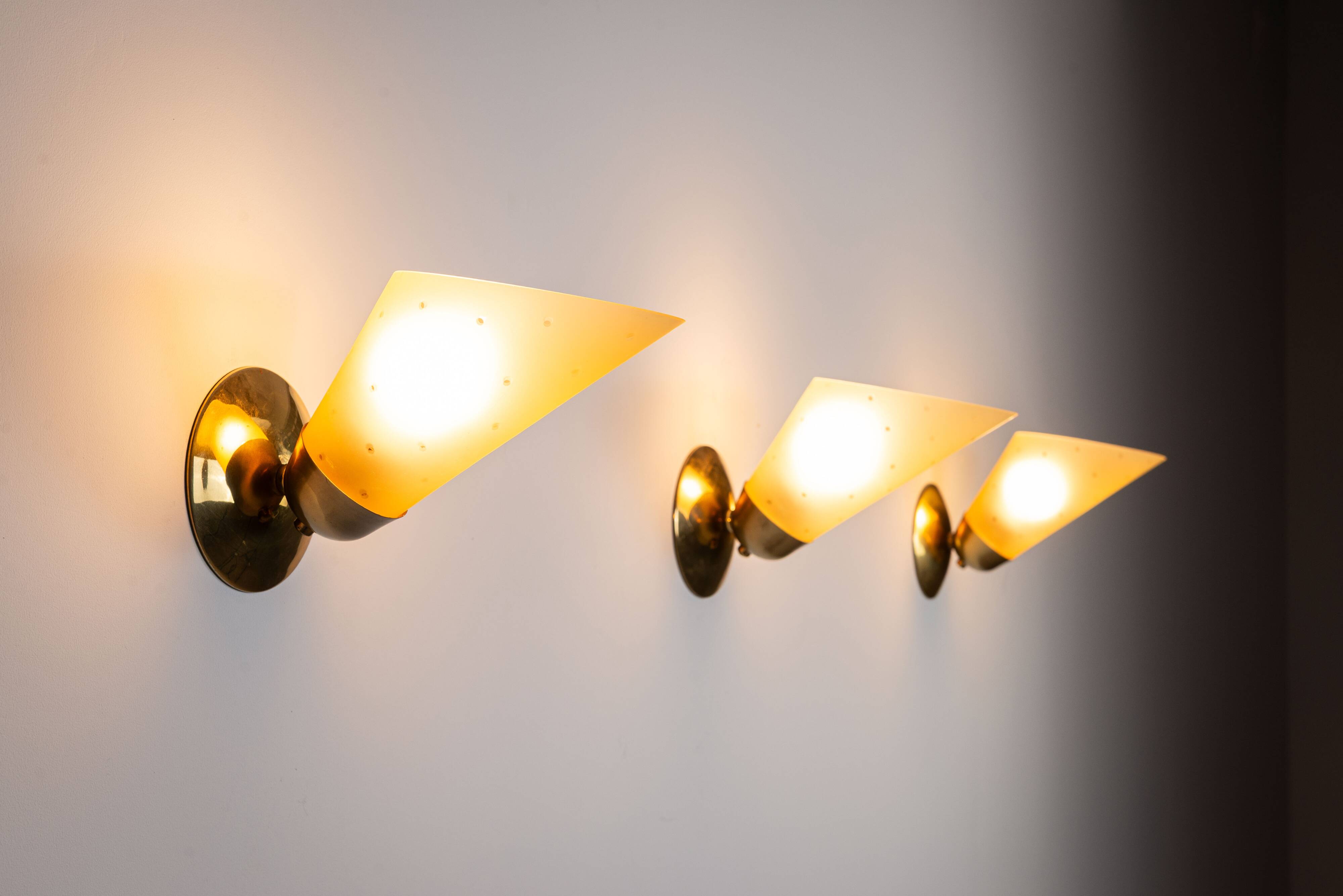 Set of three brass sconces with decorated yellow glass shades