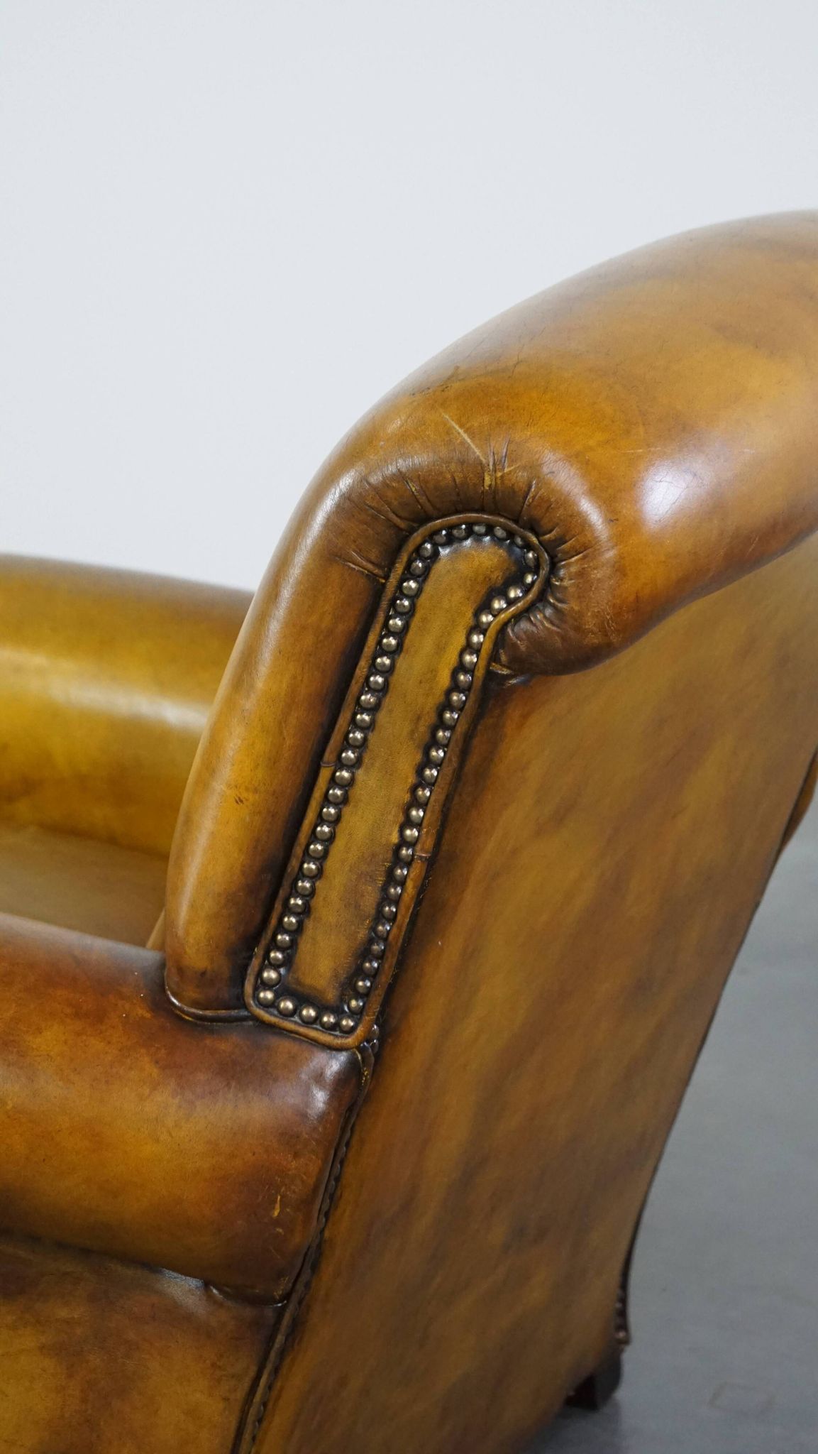 Comfortable large yellow English-style leather armchair with a fine finish and decorative nails