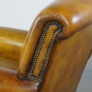 Comfortable large yellow English-style leather armchair with a fine finish and decorative nails