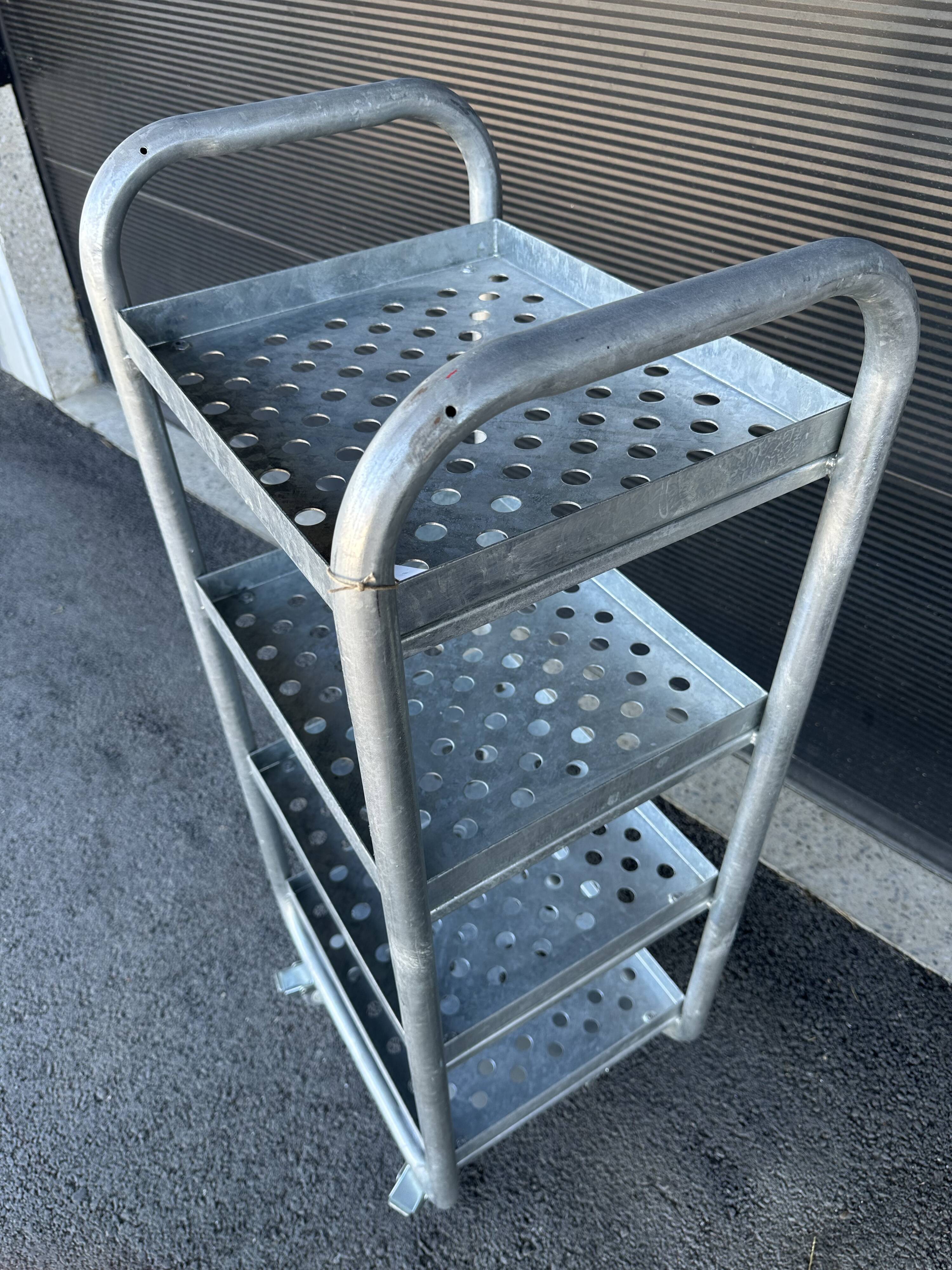 Four-wheeled dessert trolley with 4 perforated metal shelves.
