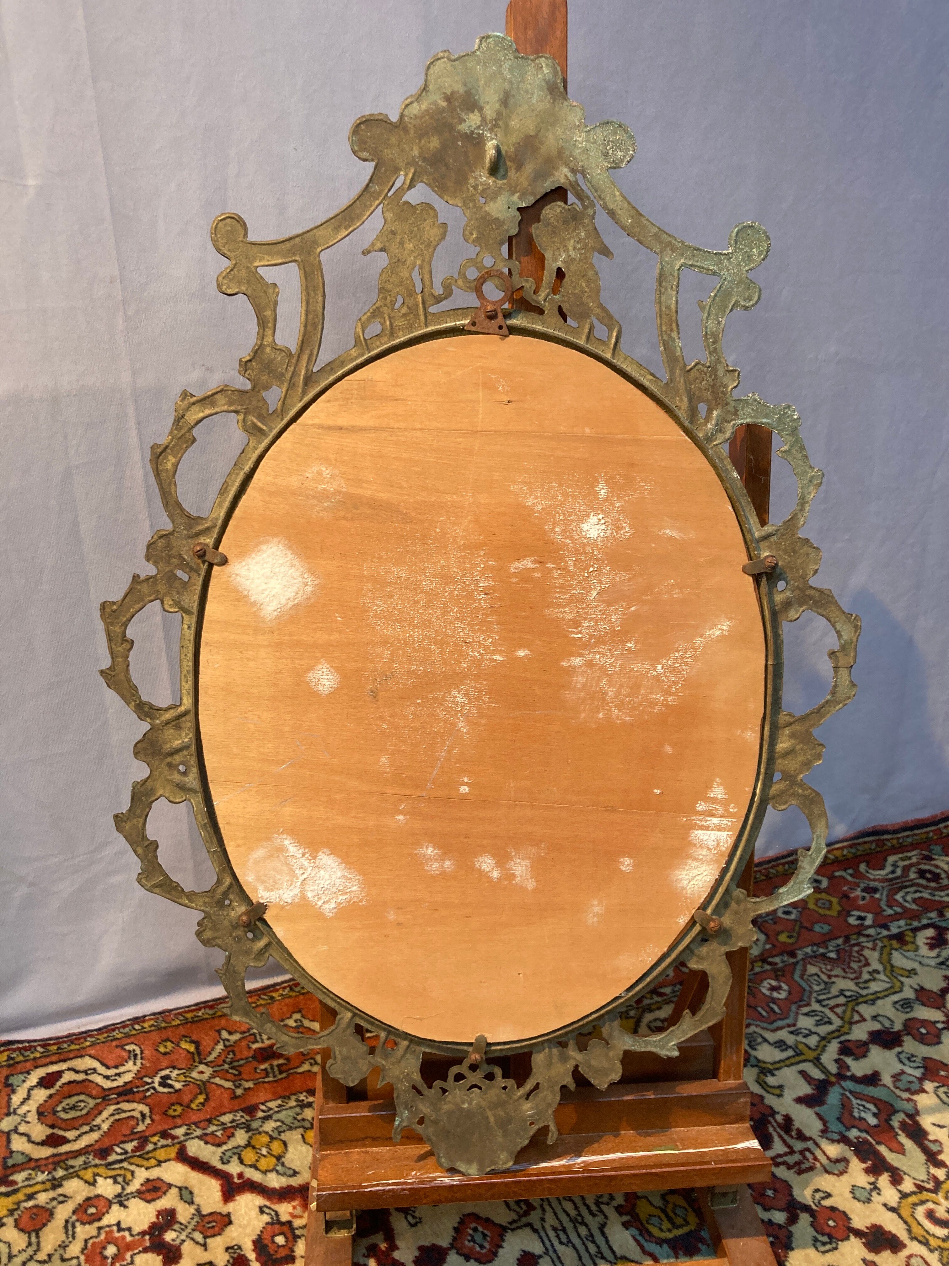 Oval mirror in gilded brass, figures of cherubs and moldings