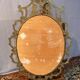 Oval mirror in gilded brass, figures of cherubs and moldings