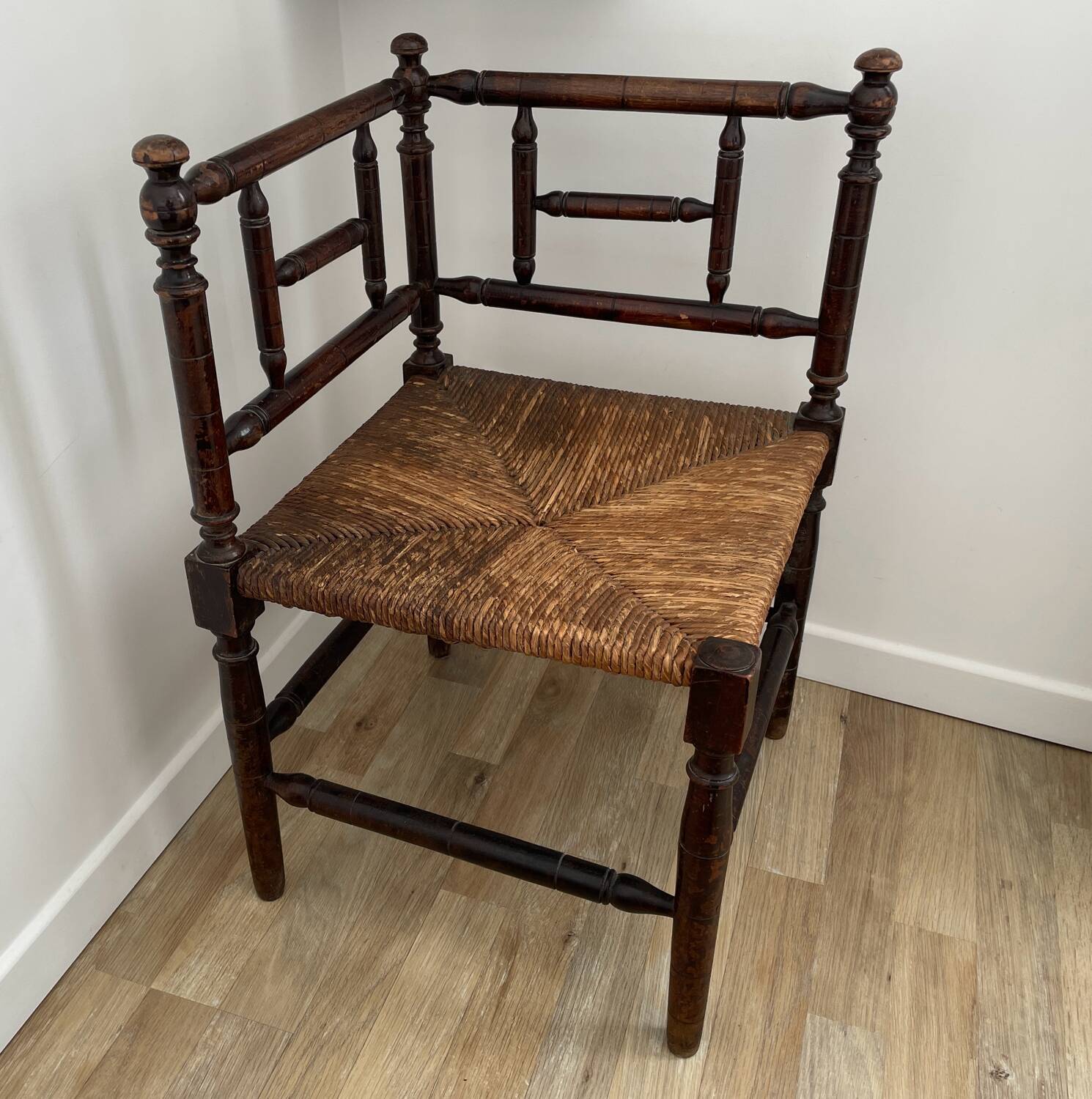 Corner chair made of turned wood with a straw seat.