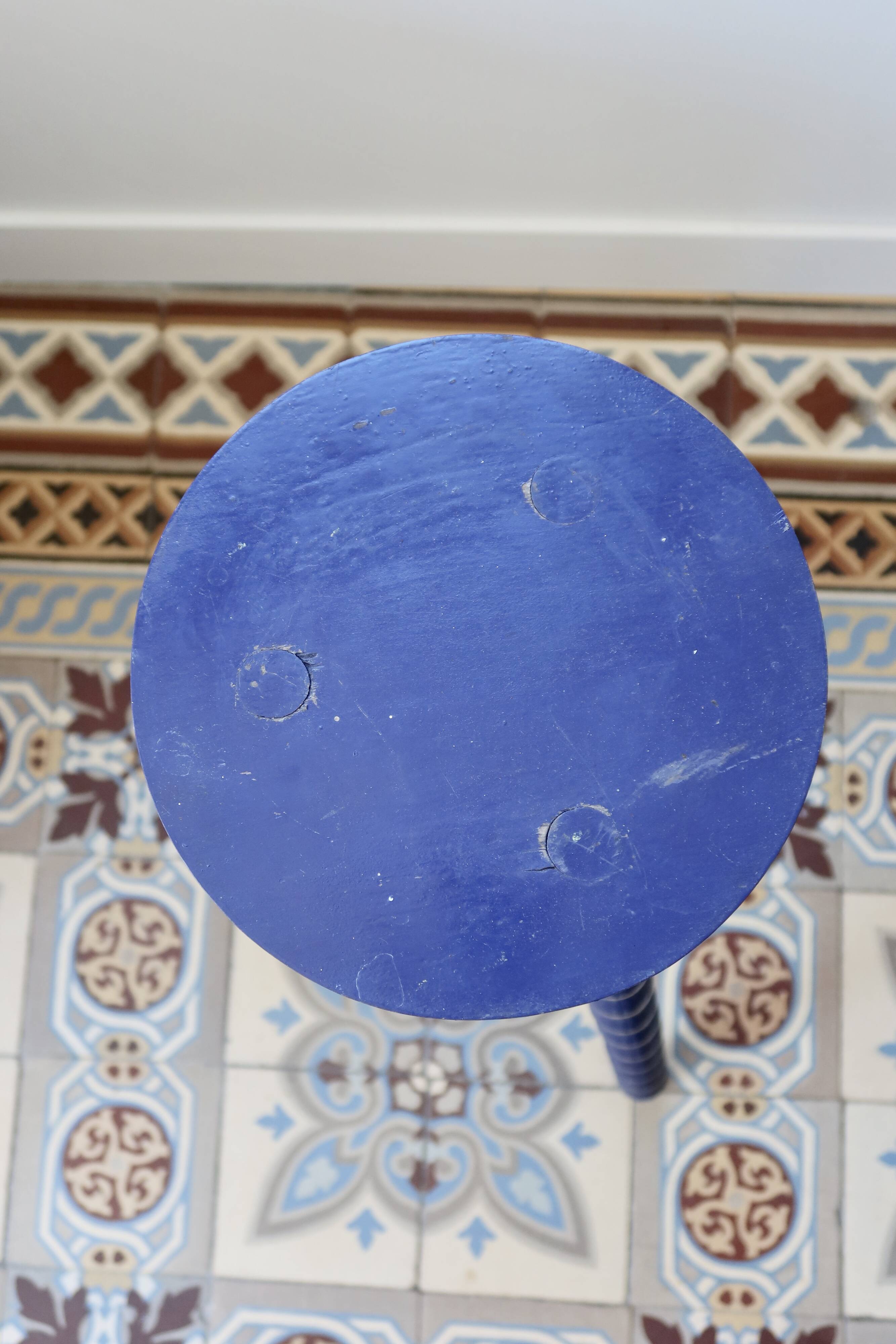 Vintage tripod stool made of turned wood, painted blue.