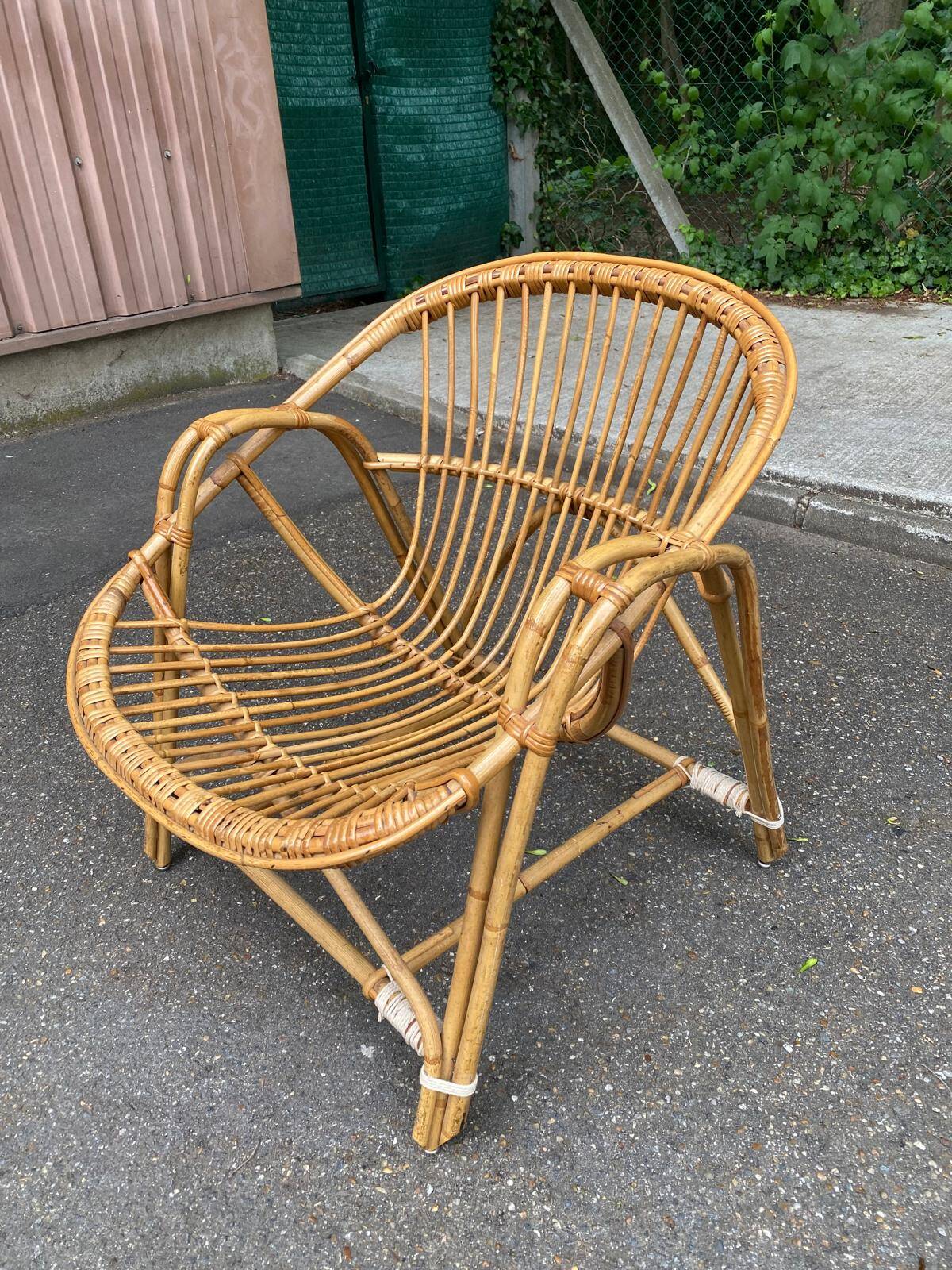 1970s adult rattan and wicker armchair with a round burgundy velvet cushion.