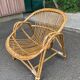 1970s adult rattan and wicker armchair with a round burgundy velvet cushion.