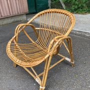 1970s adult rattan and wicker armchair with a round burgundy velvet cushion.