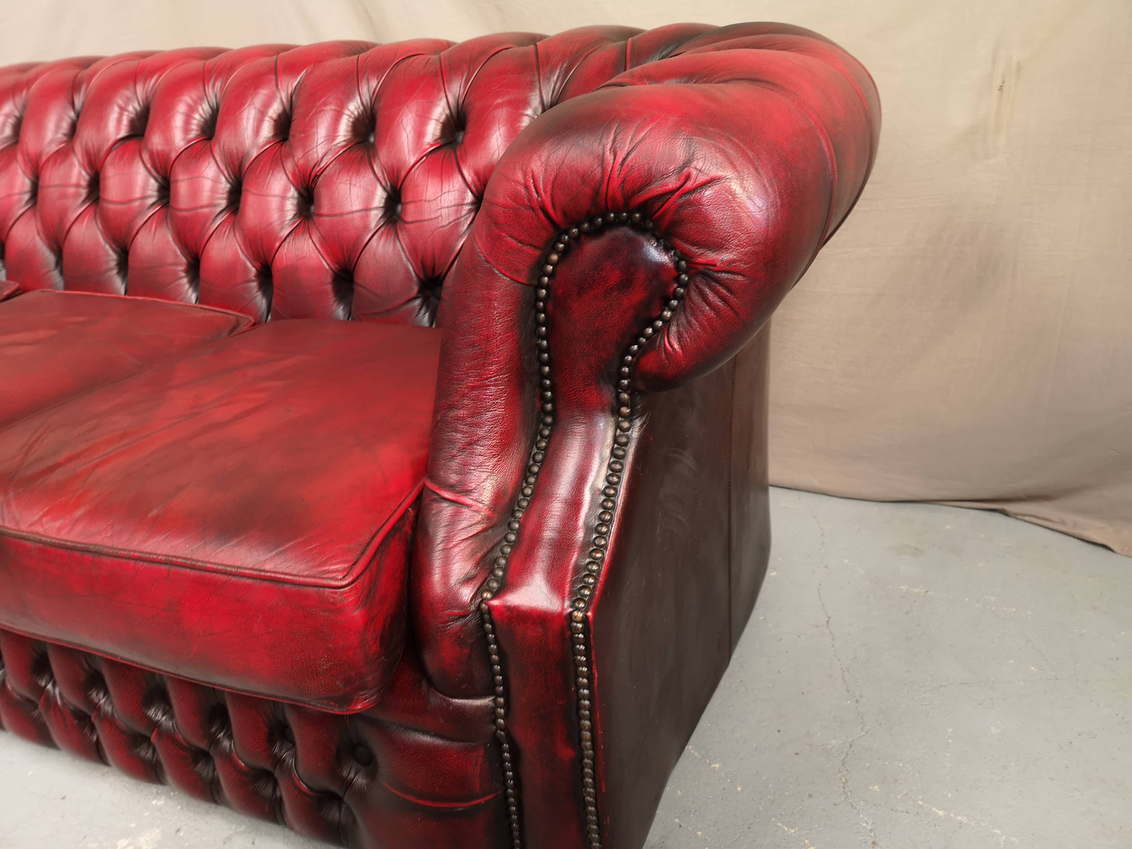 Three-seater curved red leather chesterfield sofa