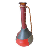 Amber bottle covered in colored leather with handle surrounded by wire, vintage