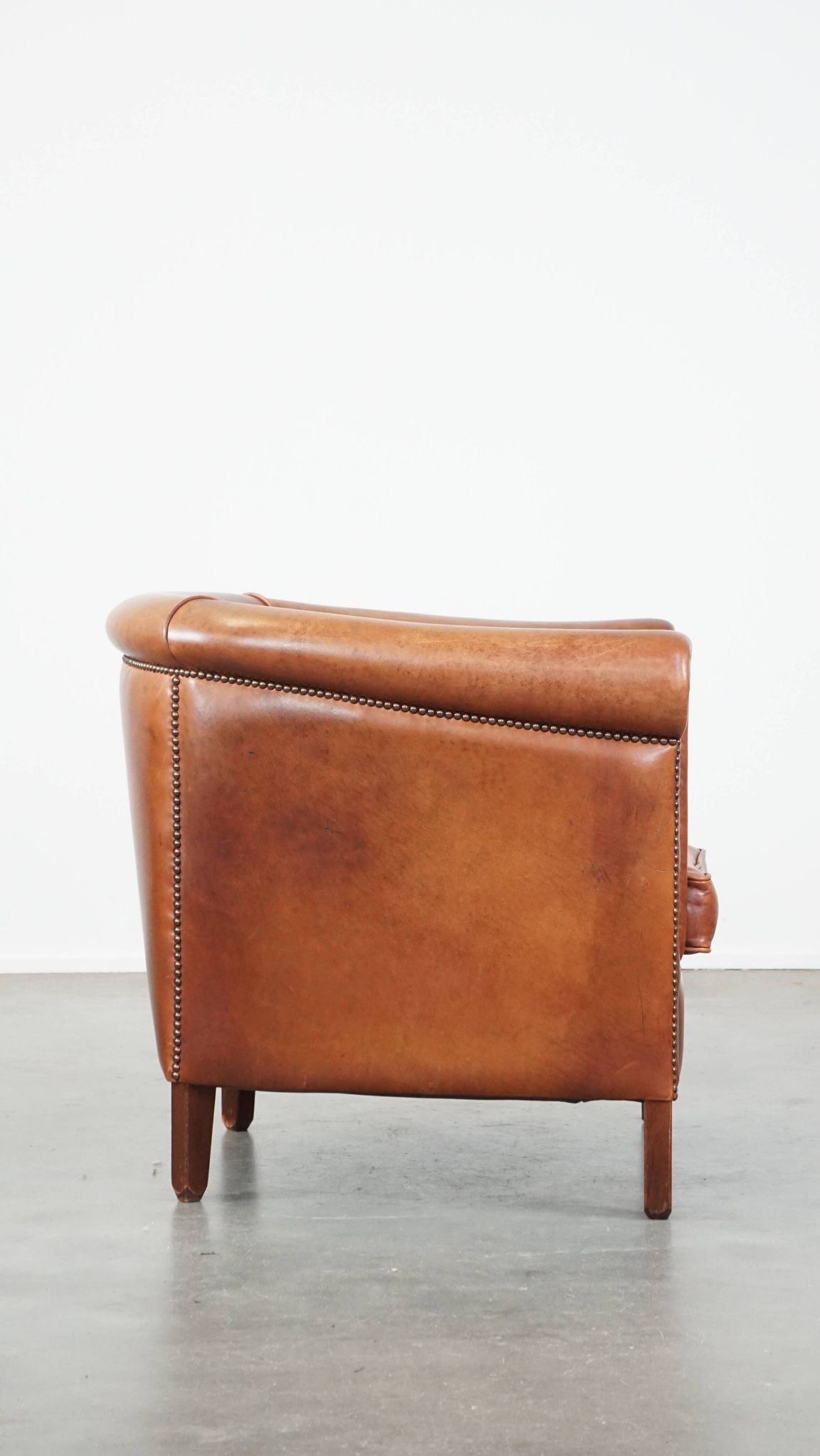 Cognac-colored cow leather club chair finished with decorative nails in English style