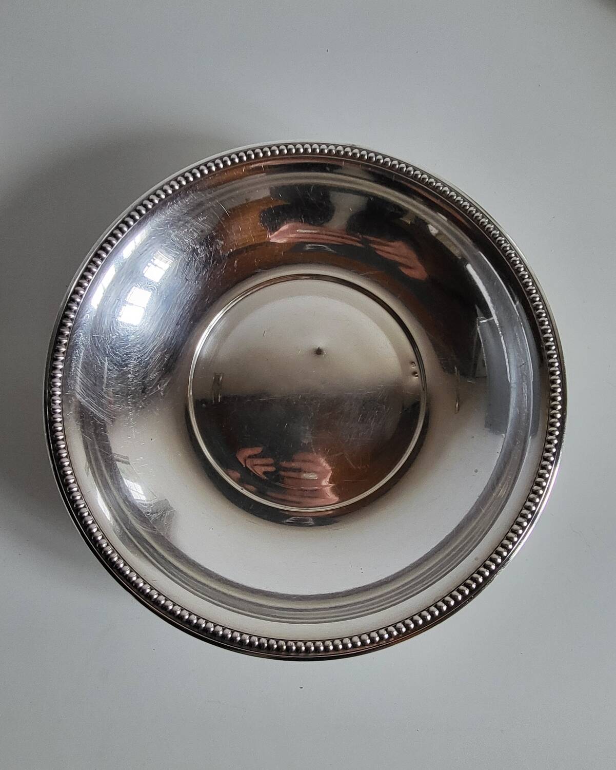 Shallow round metal plate with pearl bead decoration.