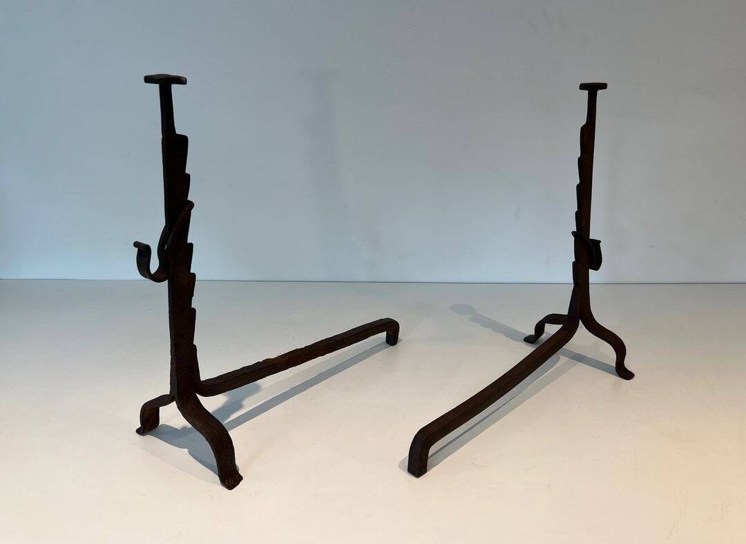 Pair of wrought iron andirons with adjustable supports and tripod feet.