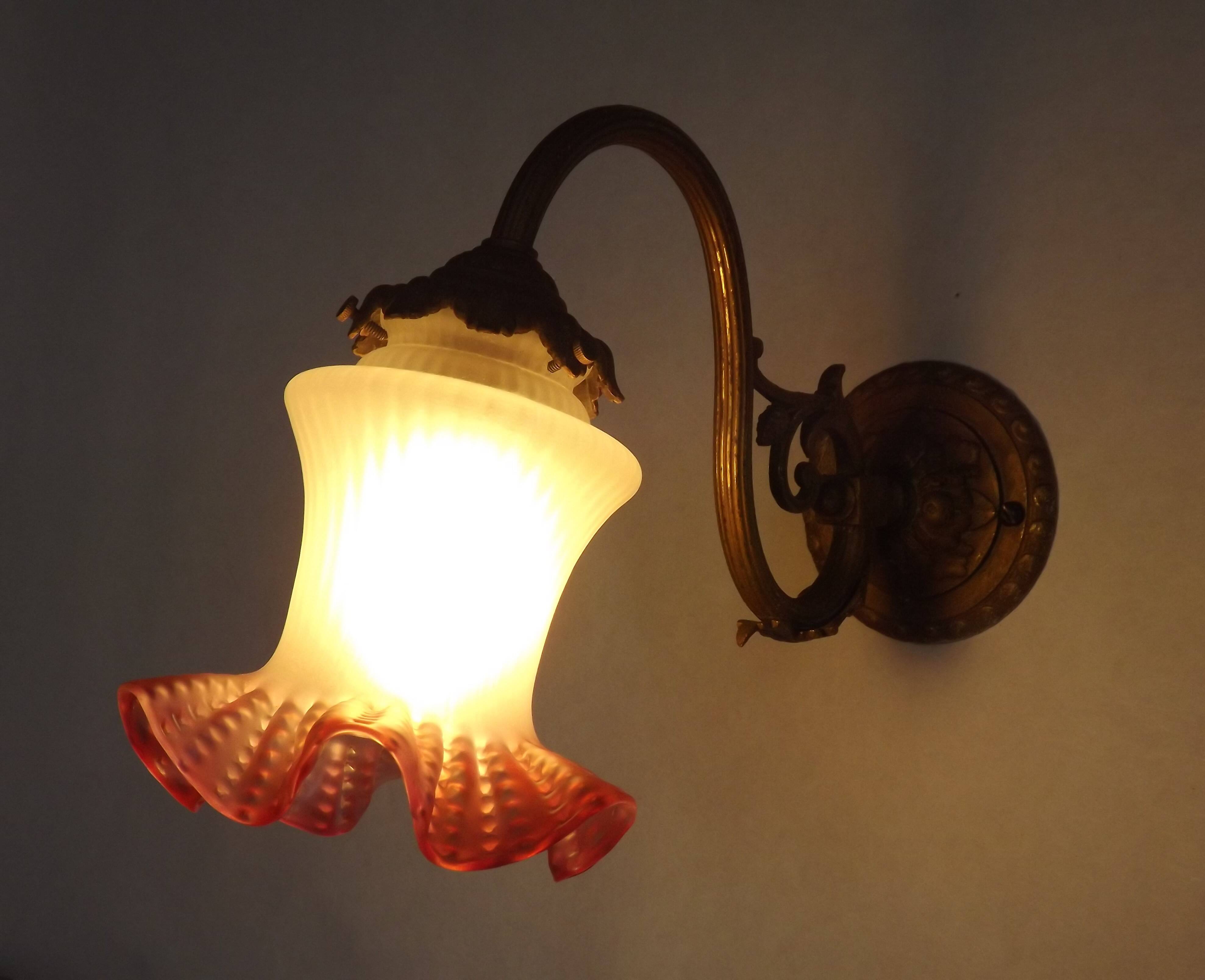 French Art Nouveau wall sconce in bronze with a white and pink glass shade.