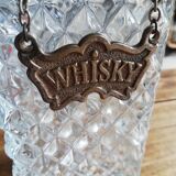 Chiseled glass whiskey decanter and its necklace marked “whiskey”